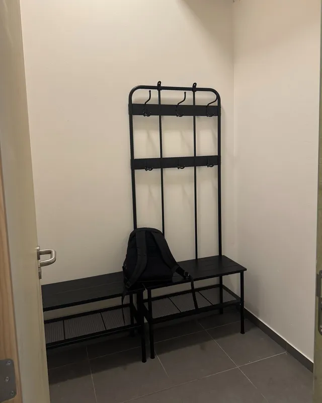 Vestiaire de la salle : banc et portants, murs blancs
