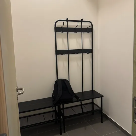 Vestiaire de la salle : banc et portants, murs blancs
